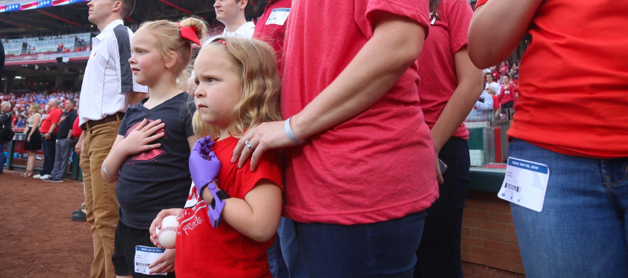 Ella morton holds her prosthetic hand over her heart during the National Anthem at Great American Ball Park.