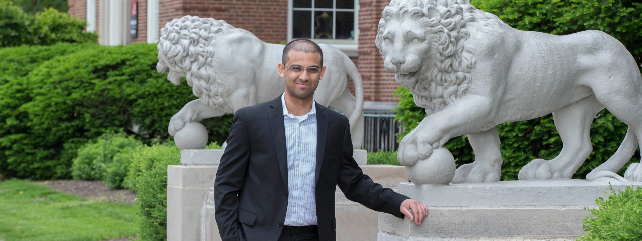 UC student Chinmay Bakshi stands between the Mick and Mack lions at McMicken Hall.