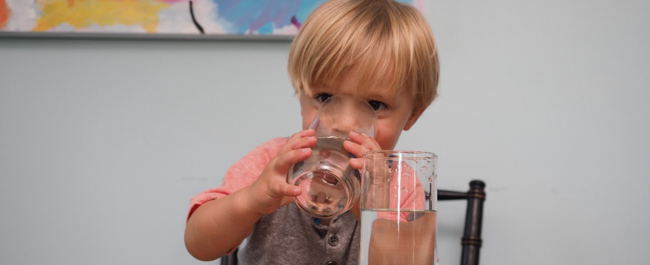 A child drinks water from a glass.
