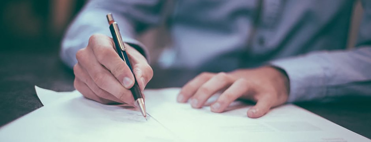 Businessman signing a paper with pen.