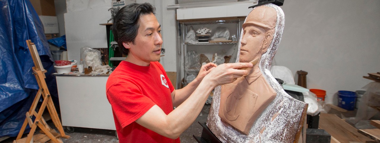 Artist Tom Tsuchiya works with a clay portrait of a Red Stockings player in his studio