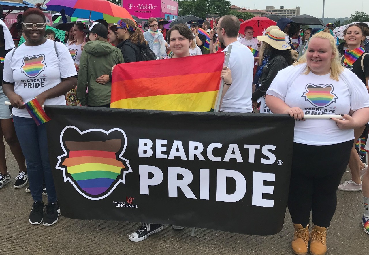 UC community members posing in a group holding a Bearcats Pride banner with rainbow Bearcat graphic.