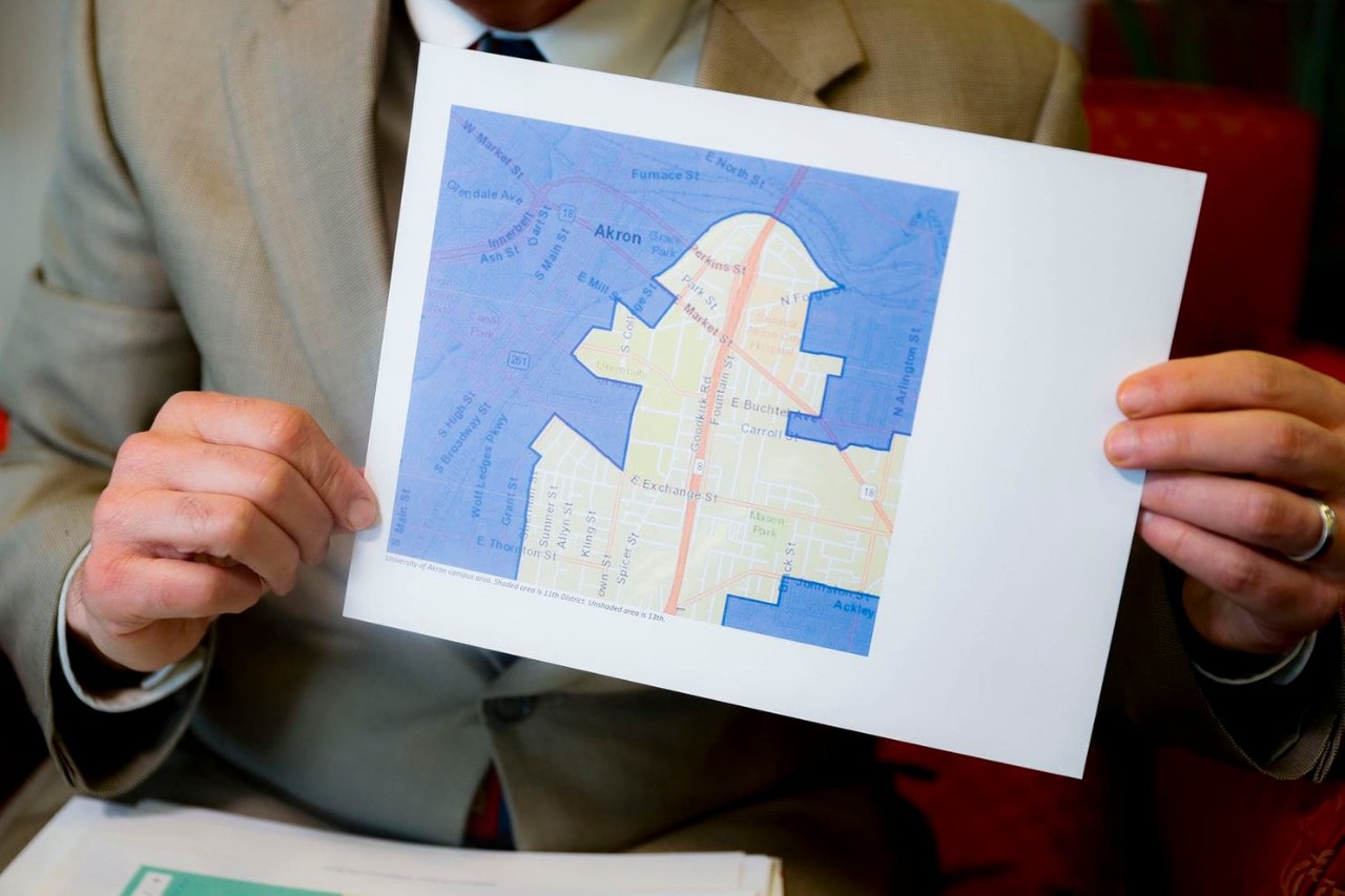 a man holds a map showing gerrymandered districts