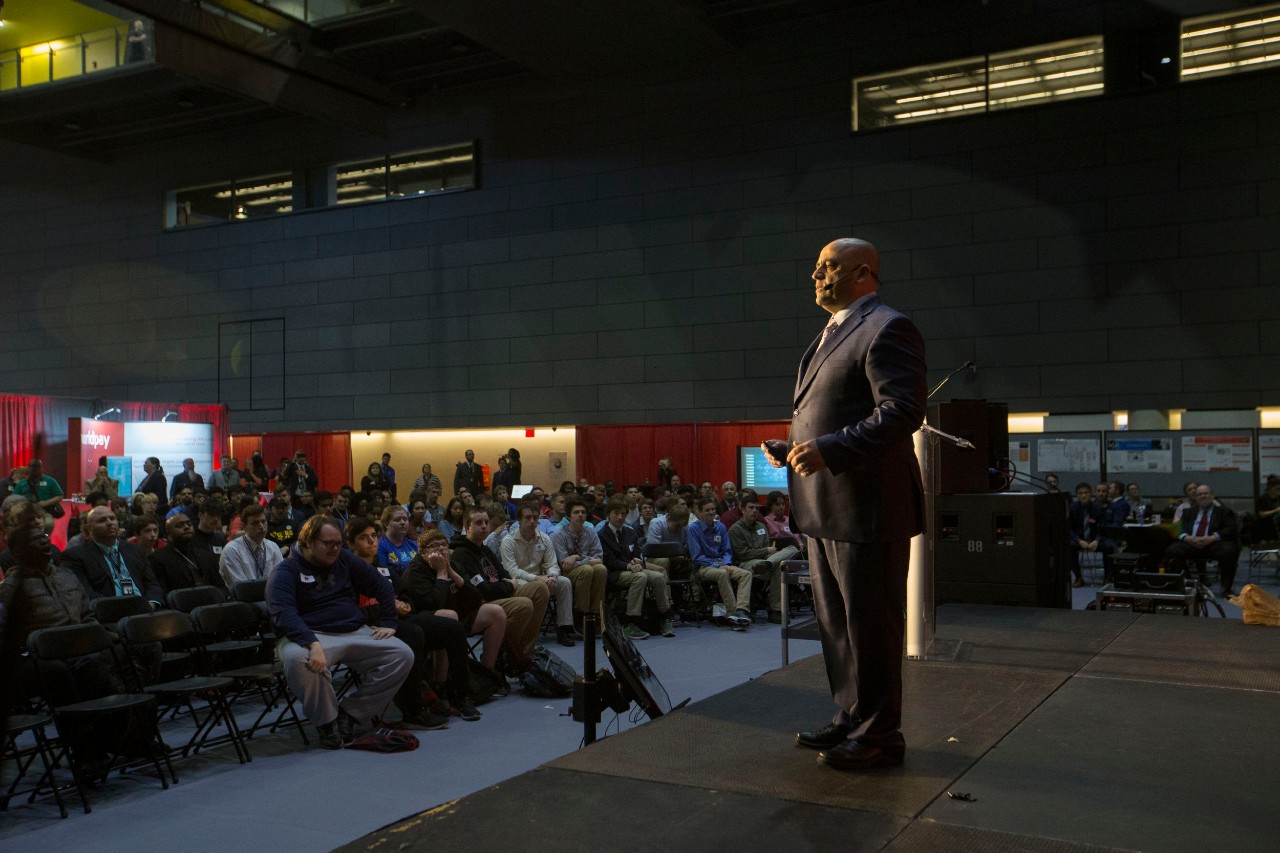 A man standing on a stage speaking before an audience