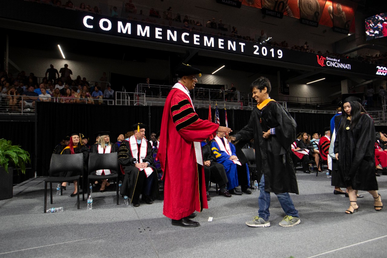 President Neville Pinto congratulates Sidharth Taneja on stage during commencement at Fifth Third Arena.