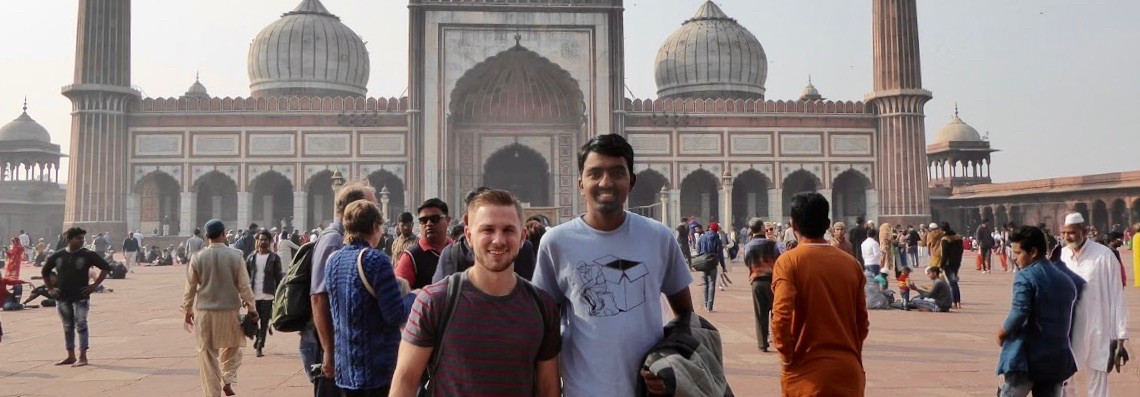 UC business grad Garrett Ainsworth stands with friend in front of government building in India.