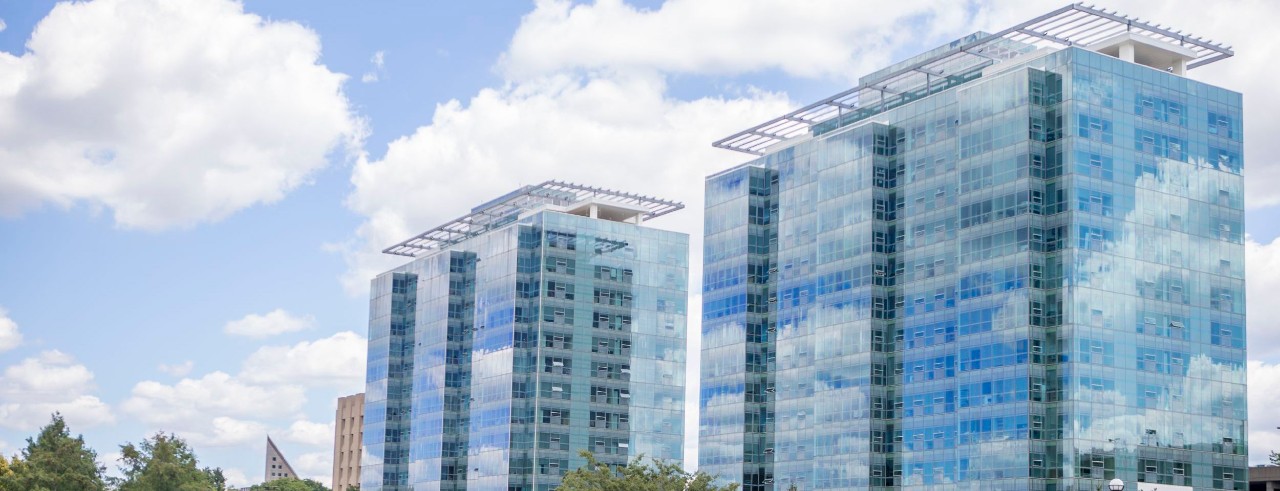 Two glass-enclosed buildings reflcting the sky
