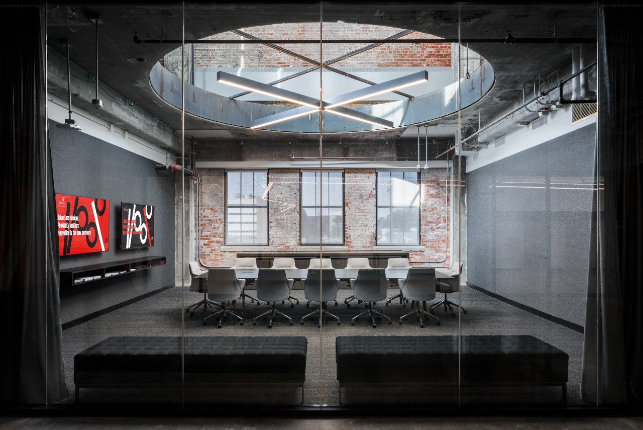 A large conference room with a circular skylight and a an exposed brick wall.