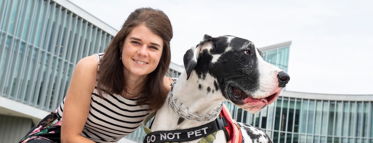 Caroline Spencer with her service dog Clark in front of the Health Sciences Building