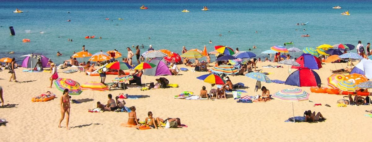 people on a sunny beach under umbrellas 