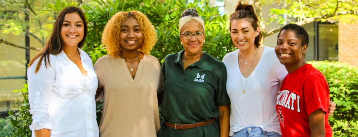 five woman stand with arms linked