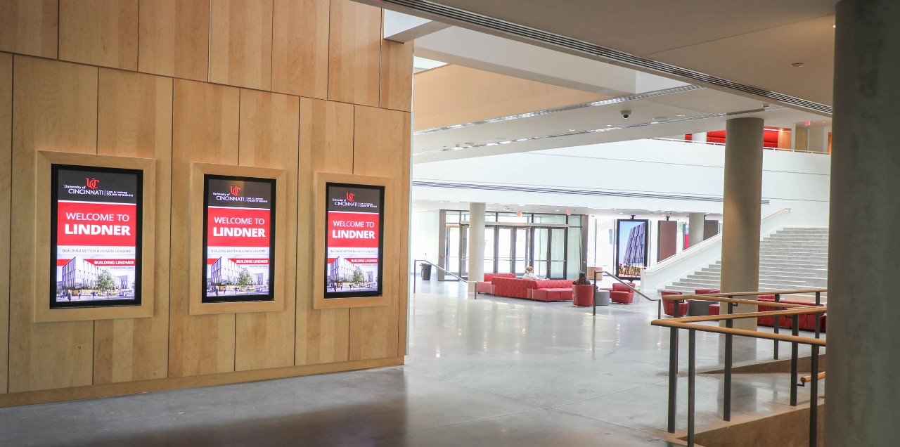 three welcome monitors are on display in a large building atrium lit by natural sunlight