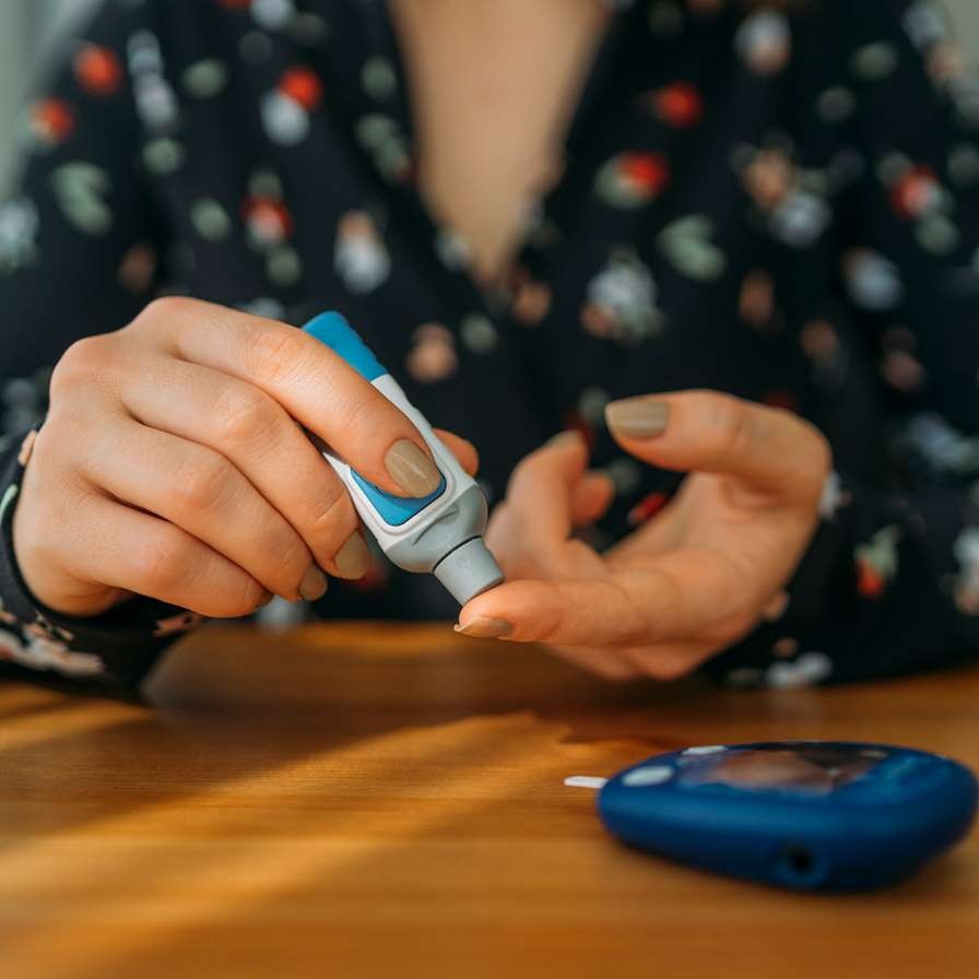 Woman sticking her finger with a diabetes testing device