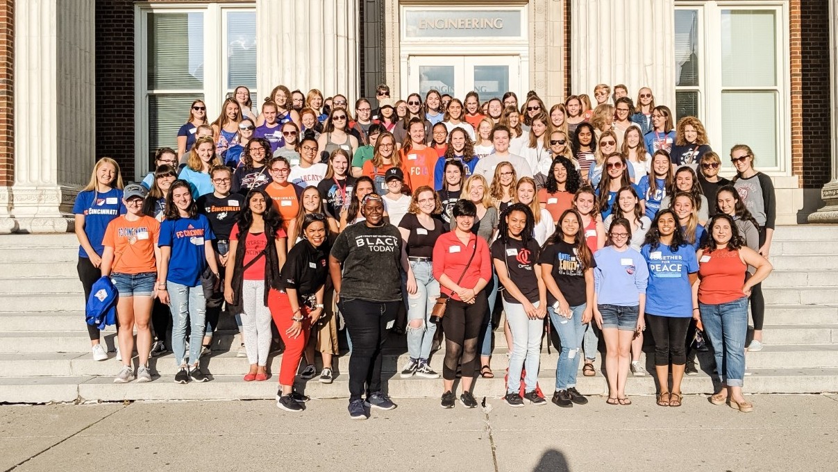 eight rows of mostly college-aged women stand on the steps in front of Baldwin Hall 