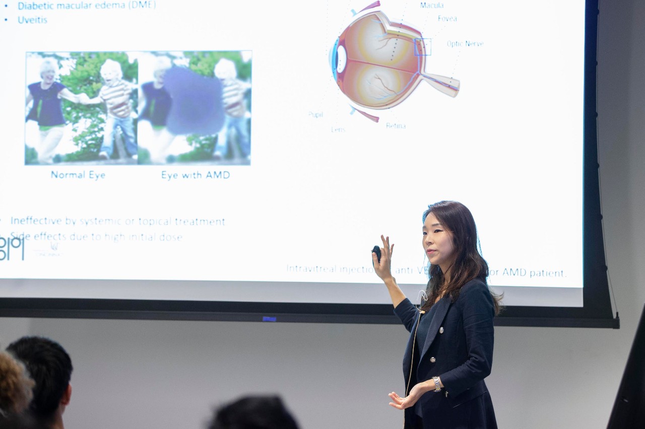 A woman gives a presentation in front of a large video screen