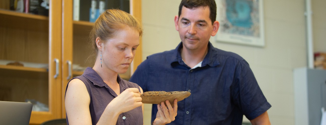 UC professor Joshua Miller and graduate student Abby Kelly examine a fossilized horse jaw in his paleontology lab.