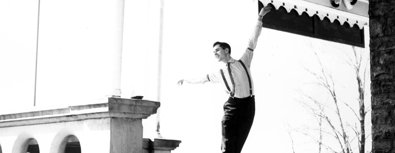 A black and white photo of a man dancing outside