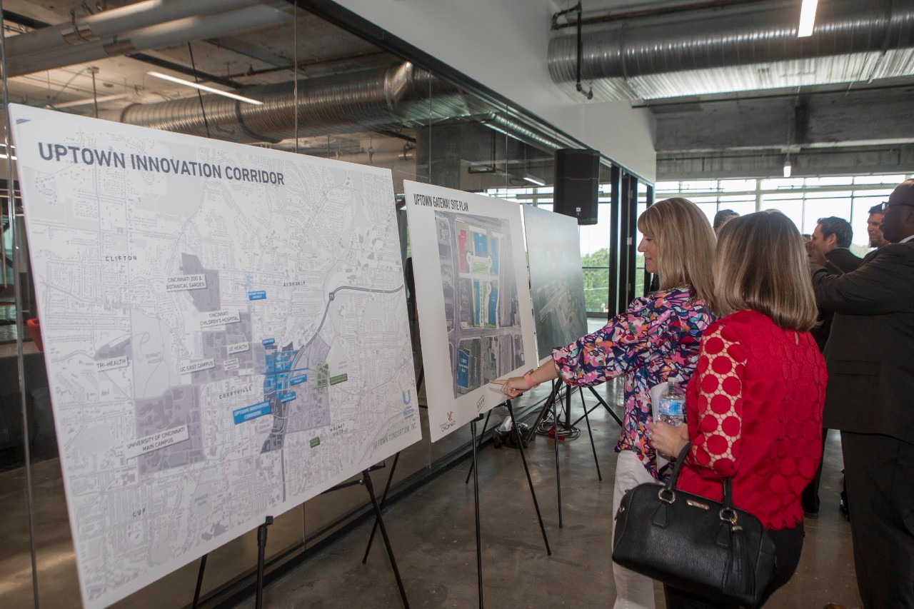 A crowd of people examine renderings and maps on large posterboards