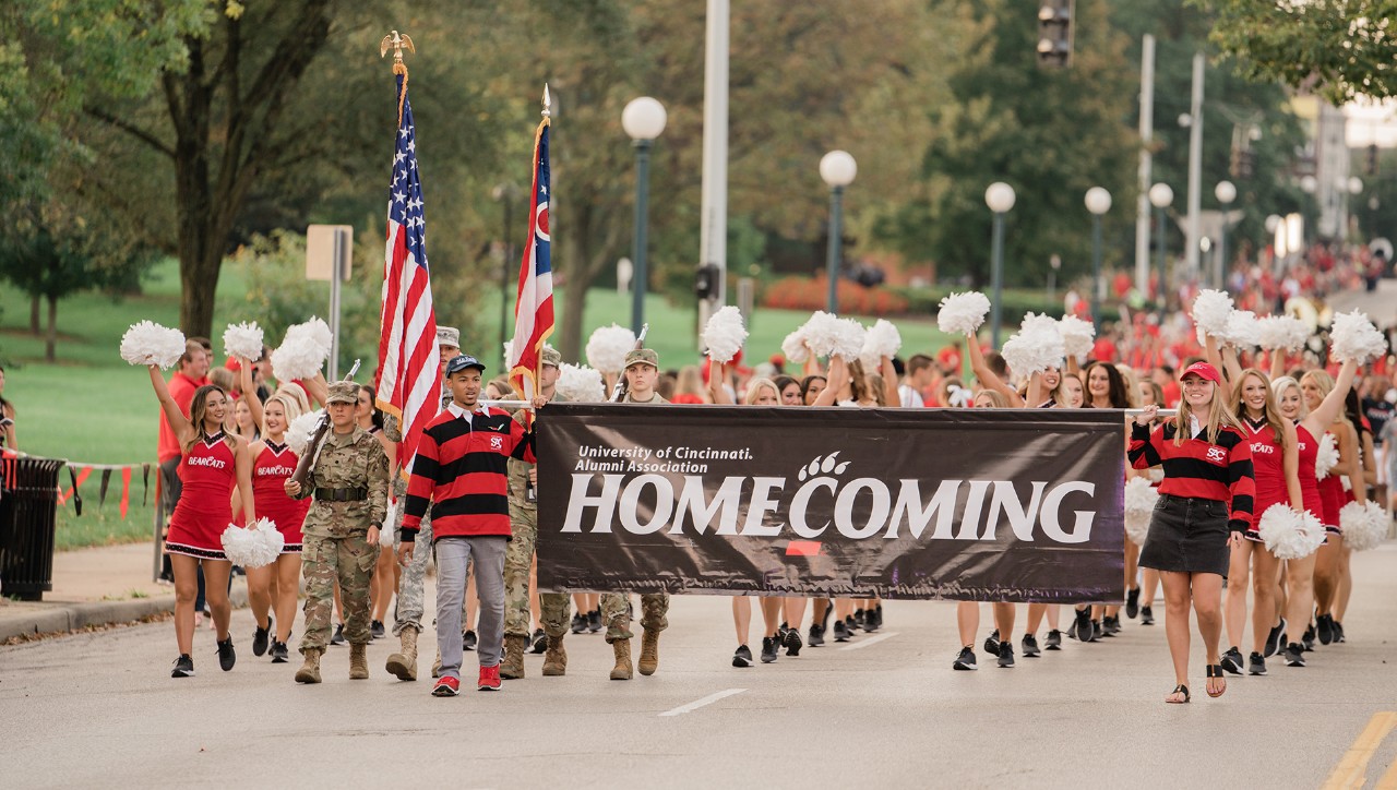 Students walk down Clifton Ave. carrying a banner for the Homecoming Parade 2018
