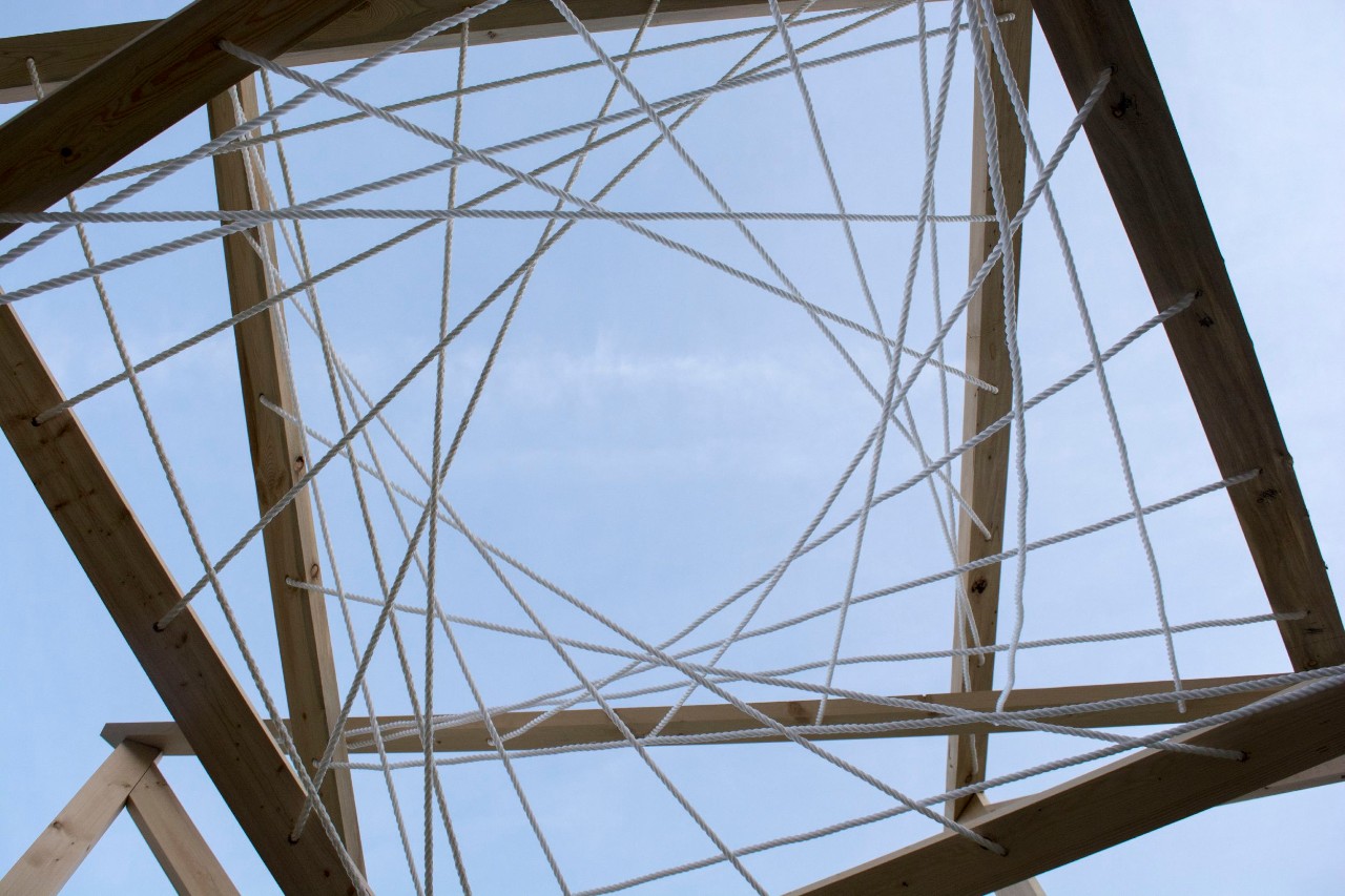 A view of the sky, looking through a sky light shaped in spirals of crossing metal beams