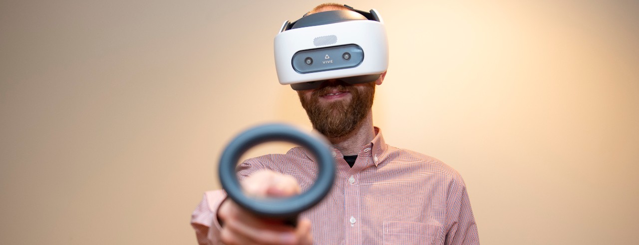 A man wearing a virtual reality headset and holding two virtual reality controllers