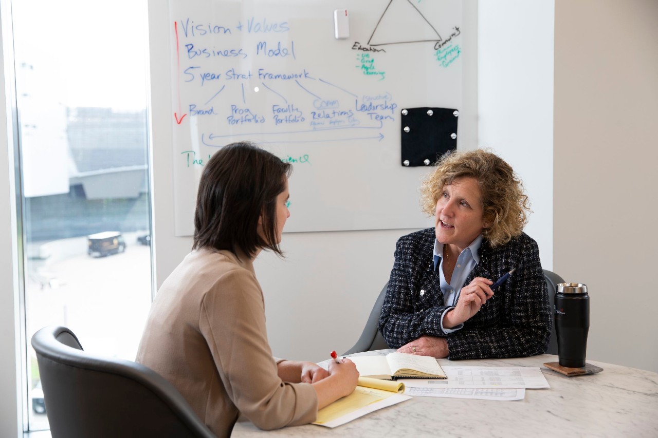 two women sitting at a table in an office