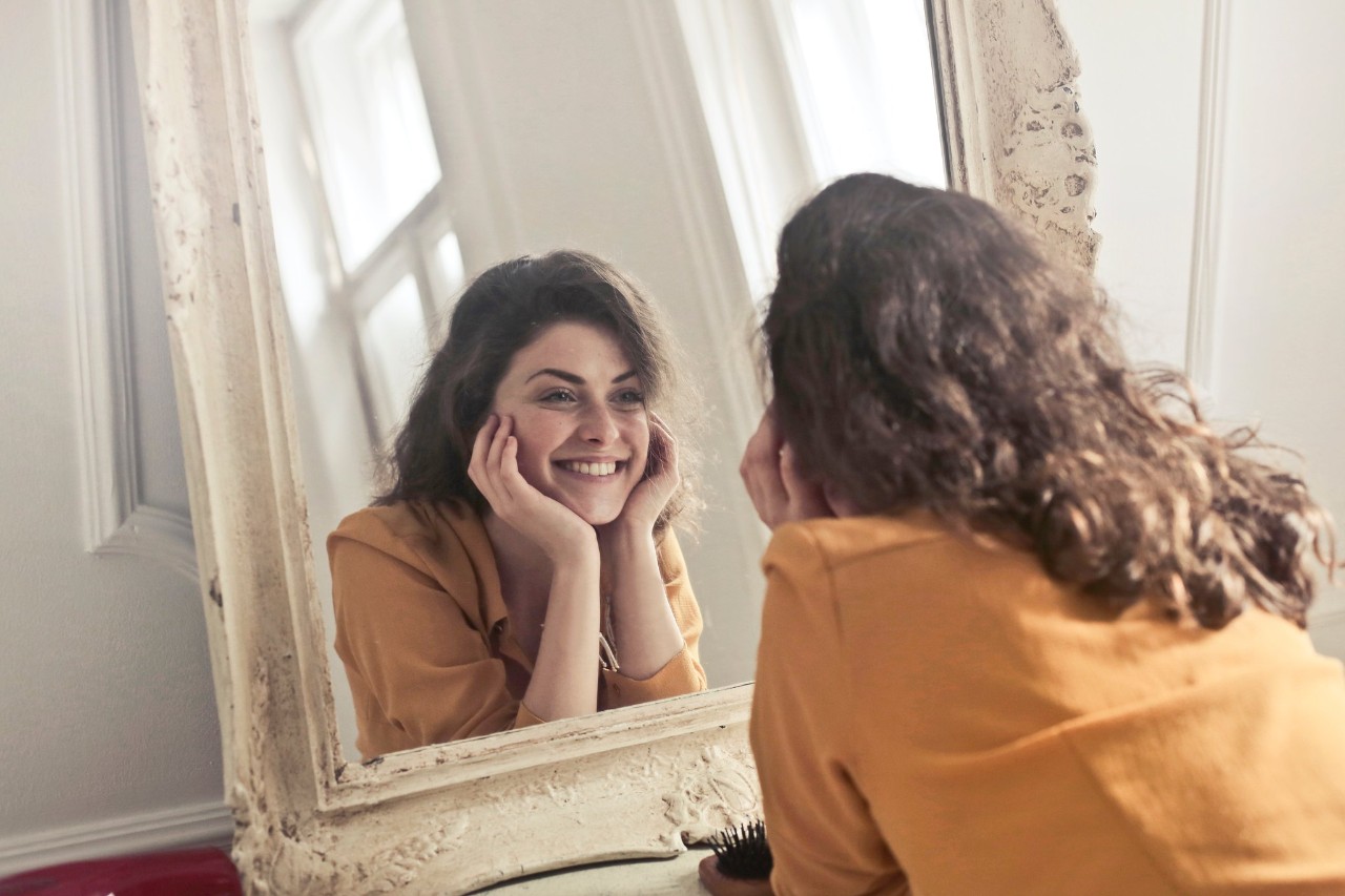 woman looking at her face in mirror