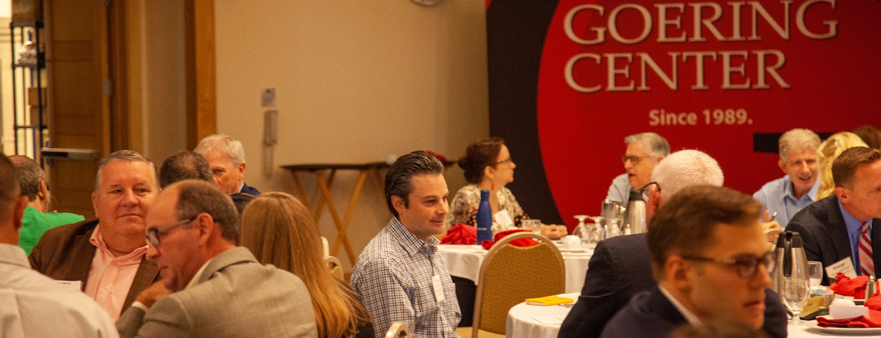 A group of business people sitting at tables discussing something at a business event.