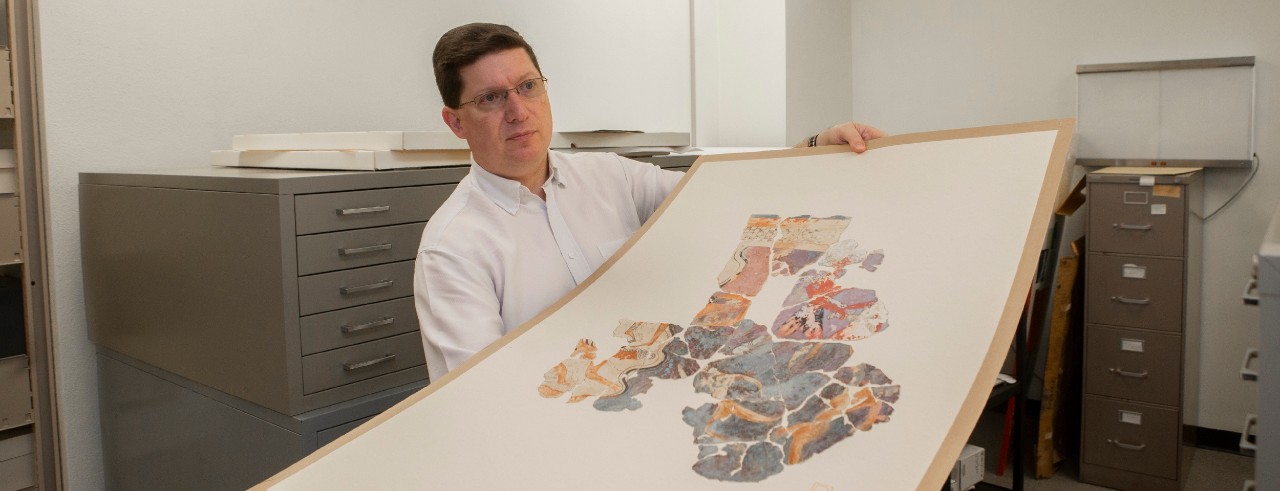 UC Classics archivist Jeff Kramer pulls out an original pottery painting commissioned during an excavation of Troy.