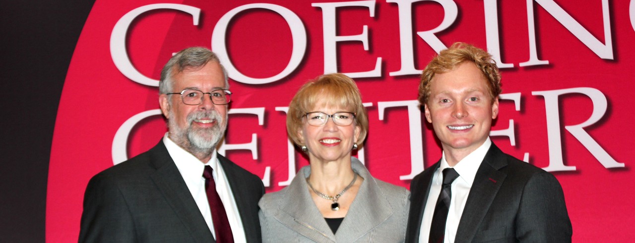 Photo of Alan Beaulieu and Connor Lokar of ITR Economics with Carol Butler of the Goering Center, posing in front of red "Goering Center" backdrop.