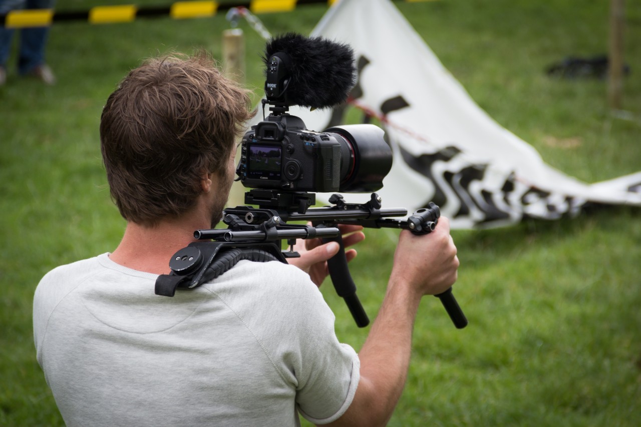 A man uses filming gear to document an event.