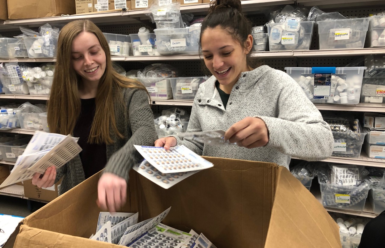 Two female students look through the contents of a cardboard box