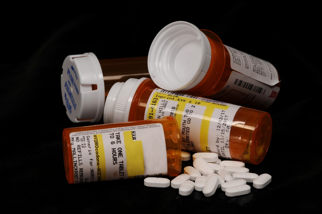 a small pile of bottles of opioids with some pills laying by them