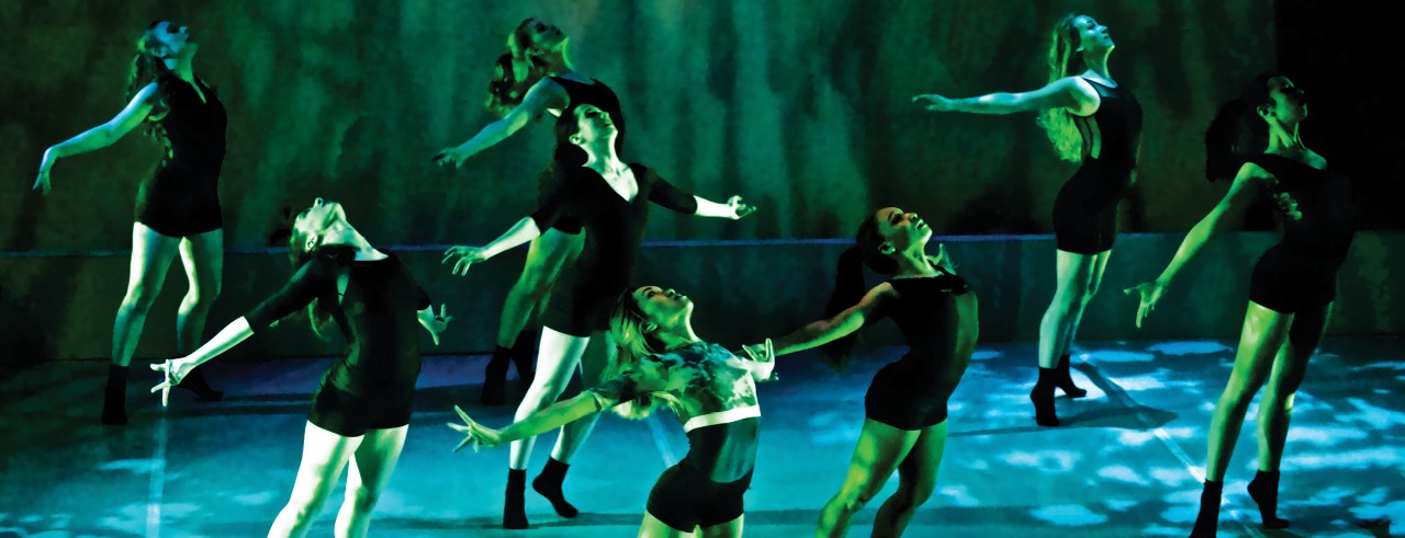 CCM student dancers perform on stage with dramatic lighting