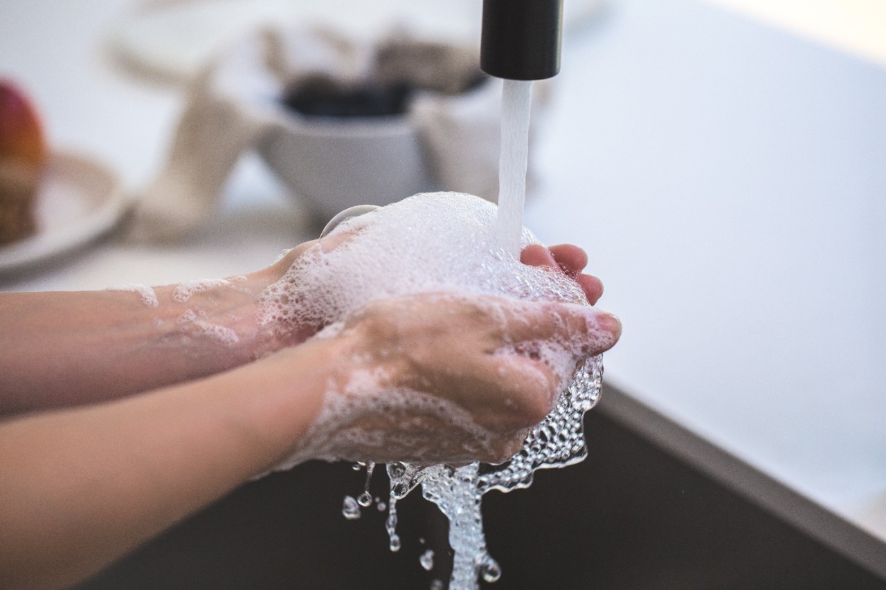 Soapy hands being washed under a faucet of running water