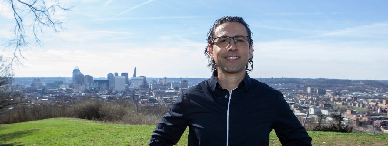 UC geography professor Diego Cuadros stands with his back to a scenic overlook of Cincinnati.