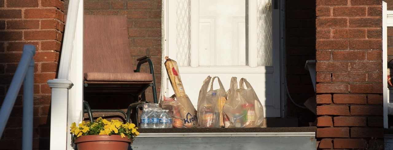 three bags of Kroger groceries on front porch of a home