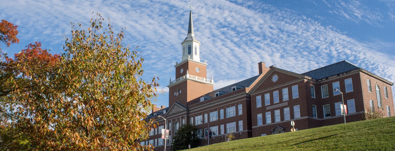 Exterior view of University of Cincinnati College of Arts & Sciences on a fall day with blue sky and autumn leaves on tree