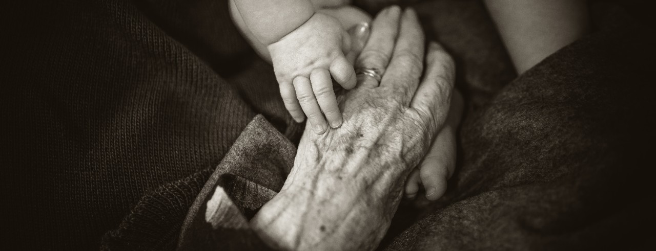 Senior citizen and baby holding hands