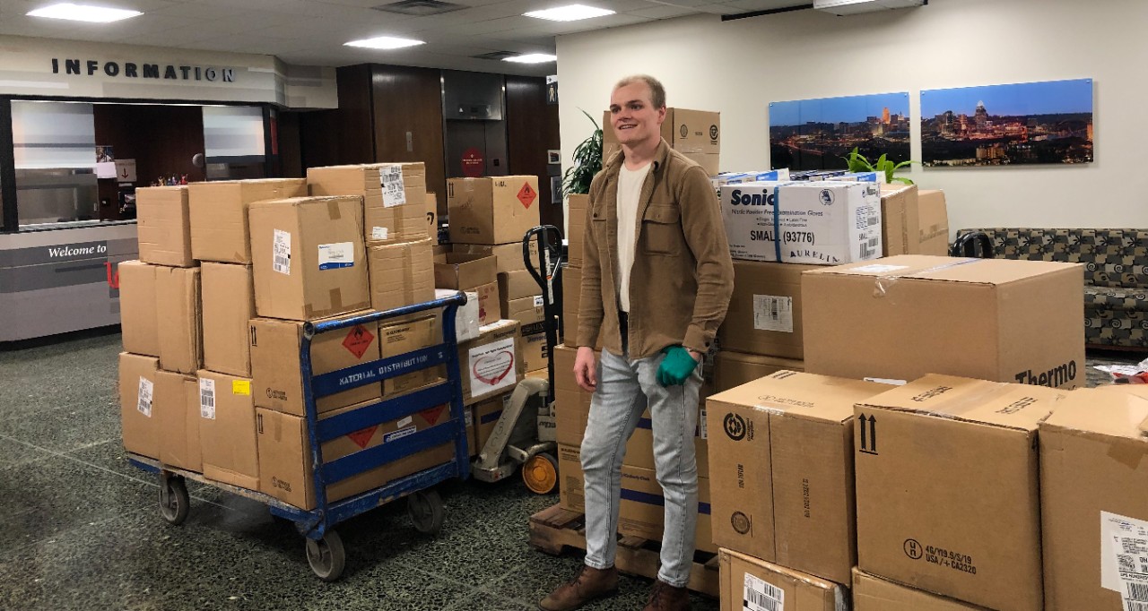 Jack Hinders stands amid boxes of donations to UC Health