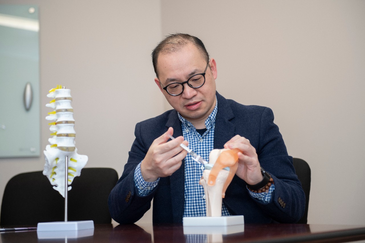 a scientist injecting a needle into a model of a spine