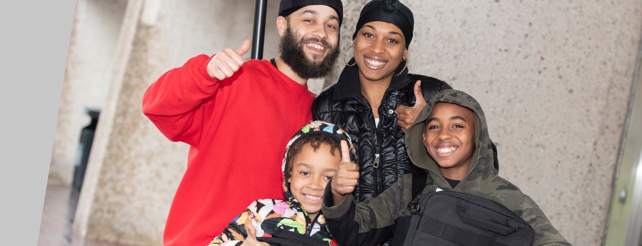 Jeremiah Hughes and his brother JaiCeon Ervin, are shown with their parents picking up a laptop from UC Med Mentors.