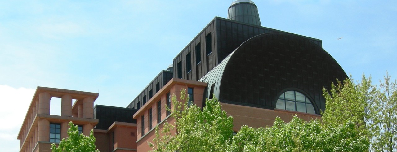 a view of the top floor of the engineering research center from the ground level during the day, with treetops in the foreground
