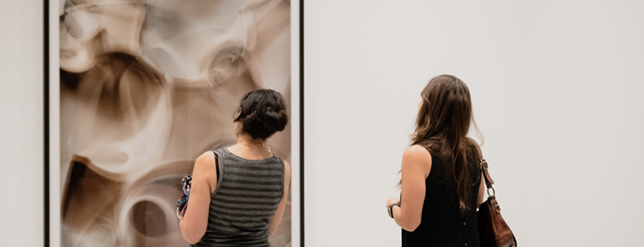 Two women look at a photograph in a gallery
