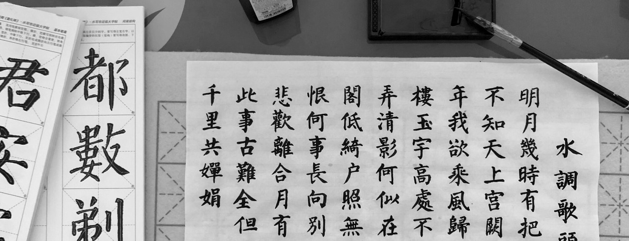 Dozens of Chinese characters on a piece of paper, with a brush and ink on table.