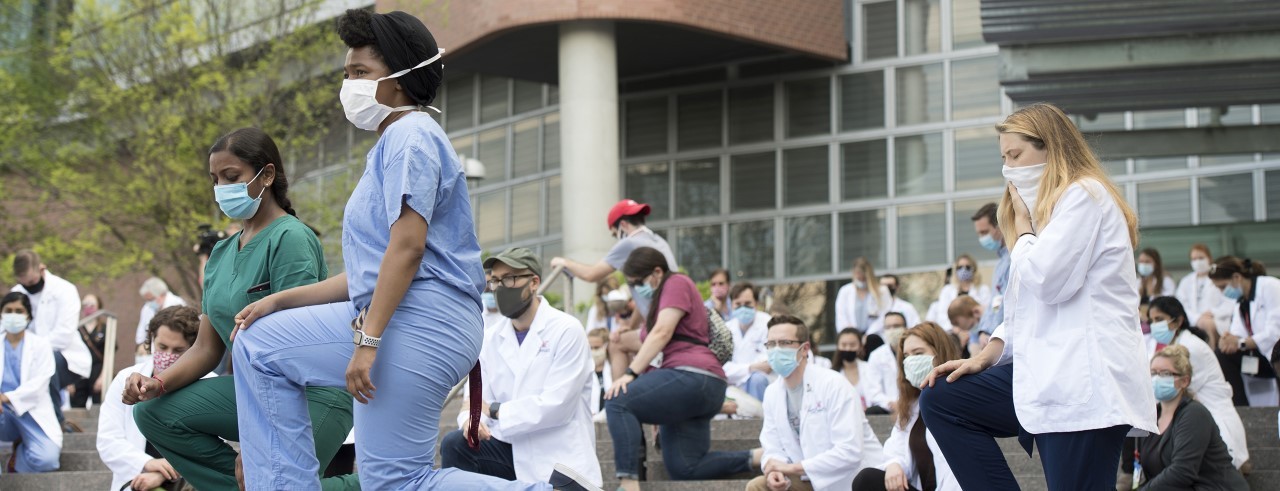 several protest kneel in front of UC College of Medicine