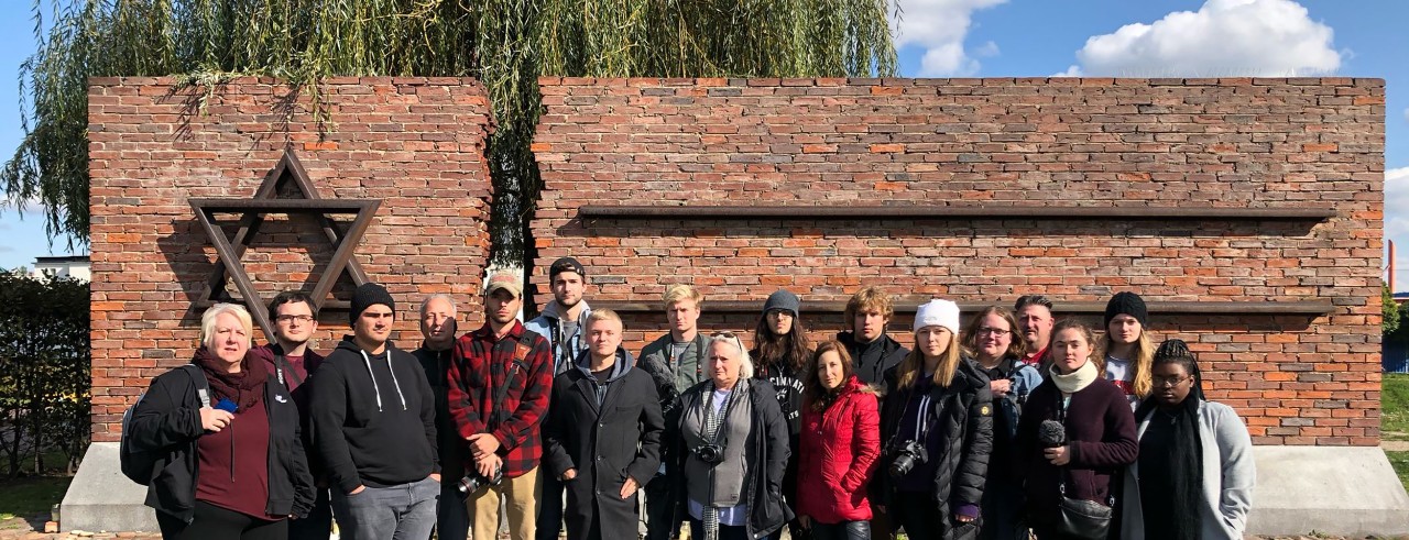 CCM Professors Hagit Limor and Susan Felder, Hagit’s brother Yoram Limor and HHC Director of Education and Engagement Jodi Elowitz stand with students in front of the monument in the Czestochowa Warta train station.
