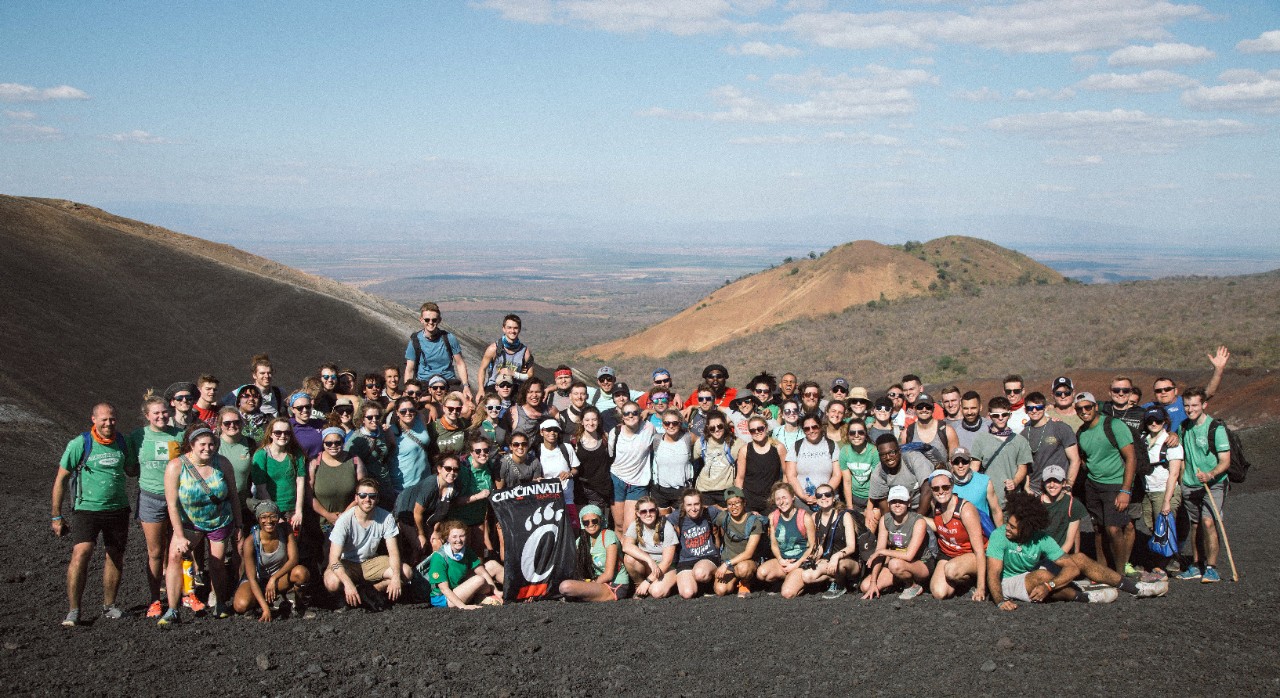 A large group of people pose for a picture in front of mountains