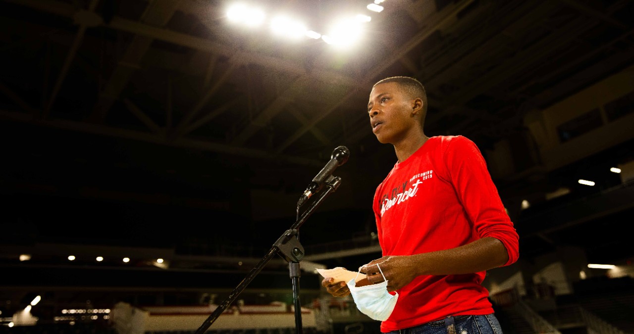 UC graduate Azaria Pittman-Carter stands on stage at an empty Fifth Third Arena reciting a poem she wrote for a taped segment to air during commencement.