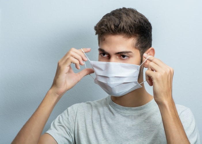 man places disposable mask on face.